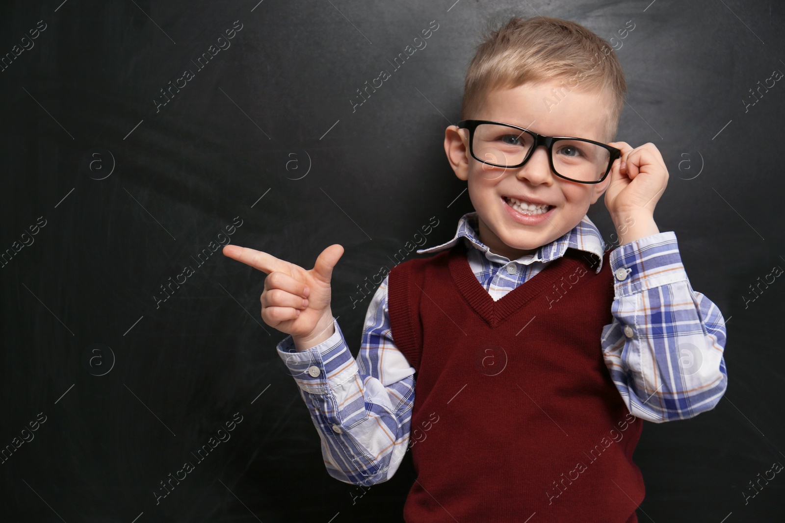 Photo of Cute little child wearing glasses near chalkboard. First time at school