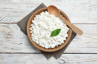 Delicious cottage cheese with basil on white wooden table, top view