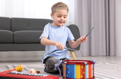 Little boy playing toy drum at home