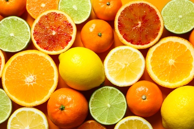 Different citrus fruits on color background, top view