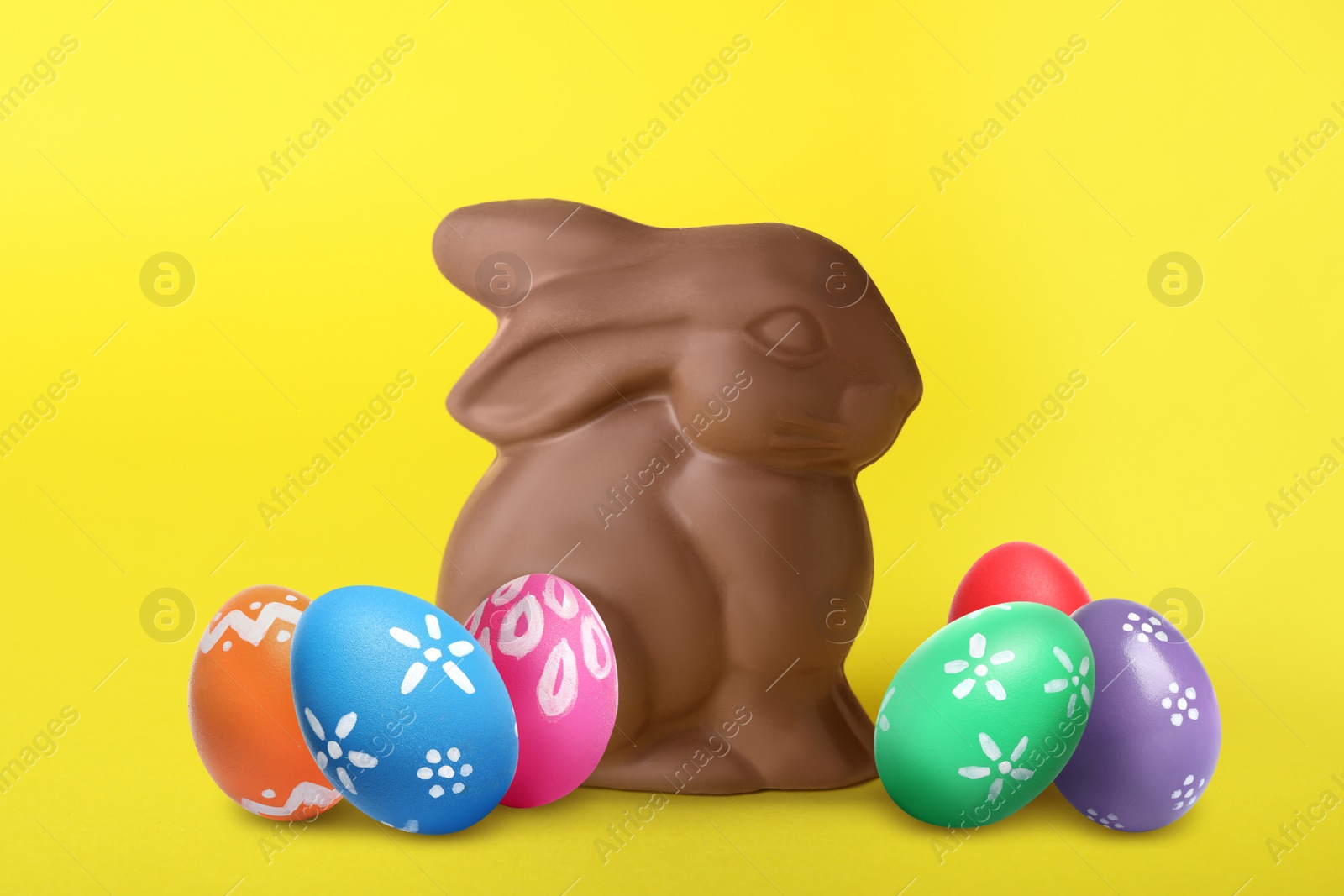 Image of Chocolate bunny and painted Easter eggs on yellow background