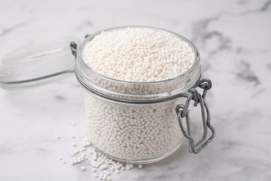 Tapioca pearls in jar on white marble table, closeup