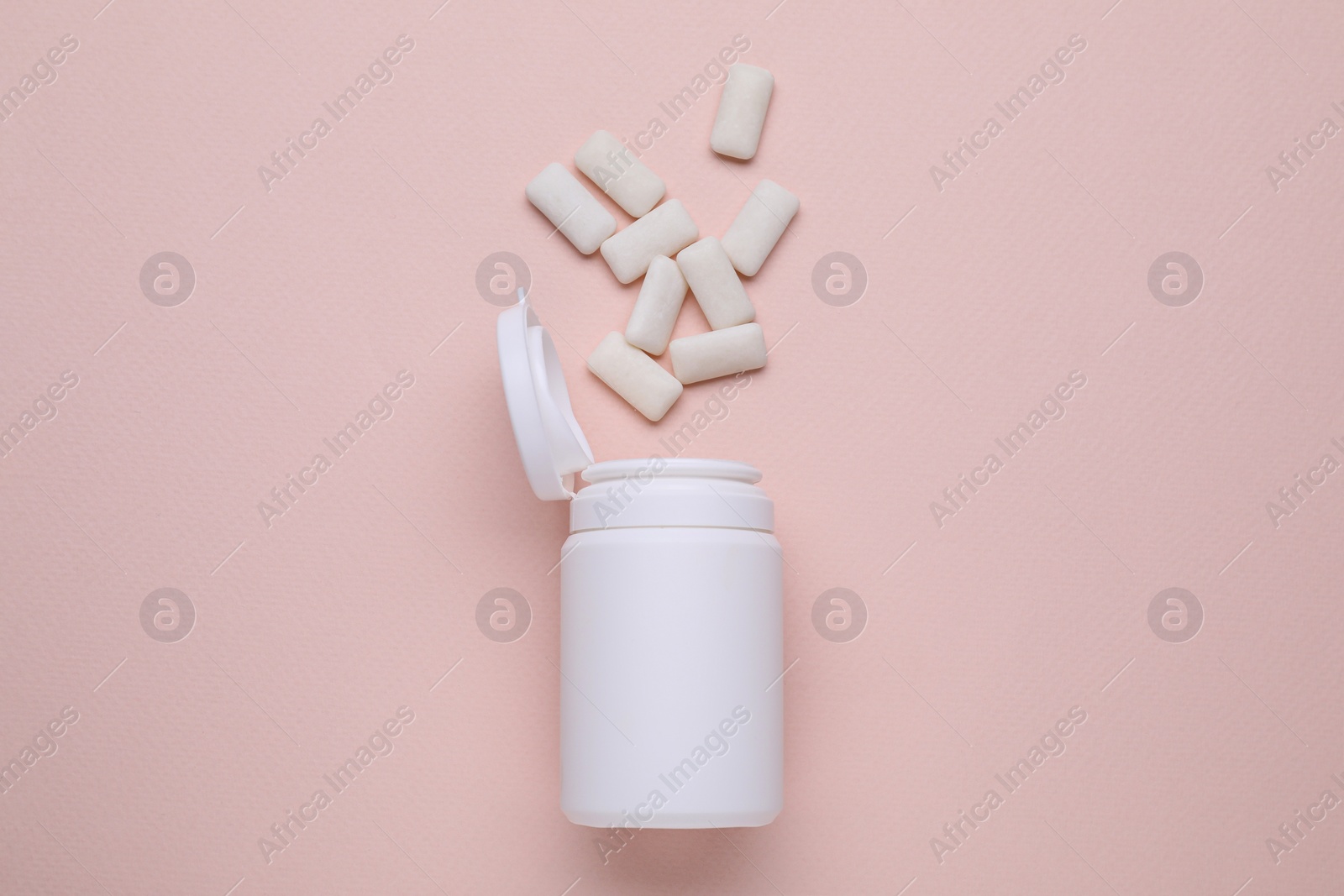 Photo of Jar with chewing gums on light pink background, flat lay