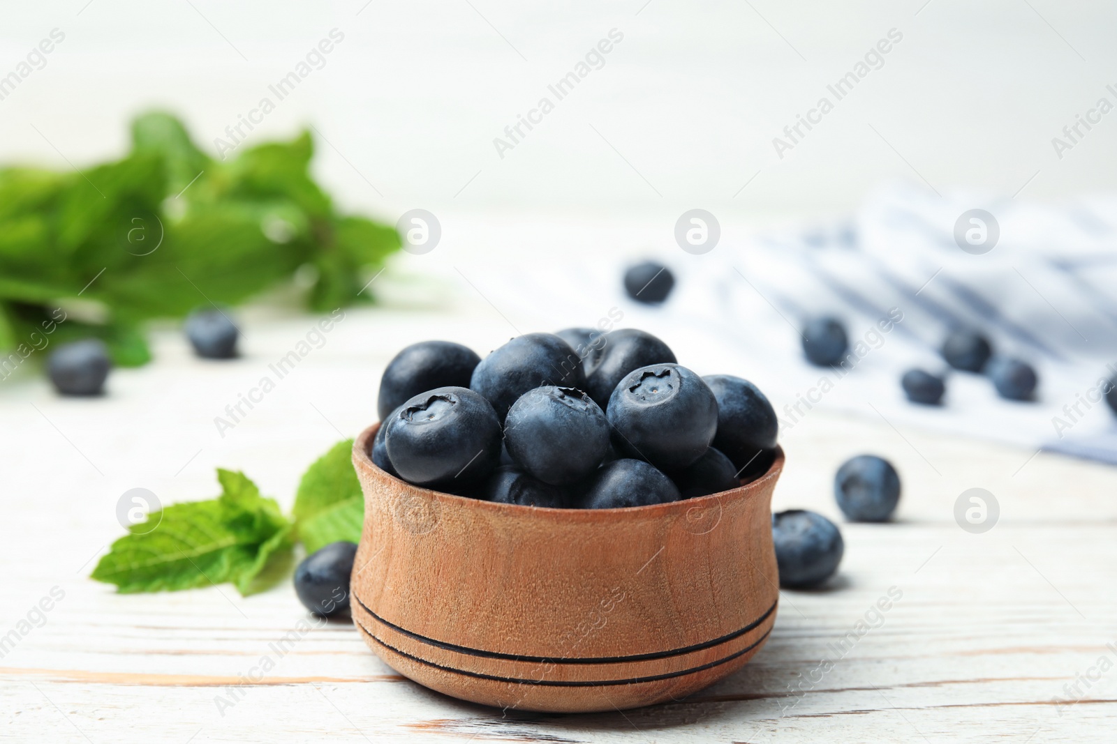 Photo of Wooden bowl with tasty blueberries on white table
