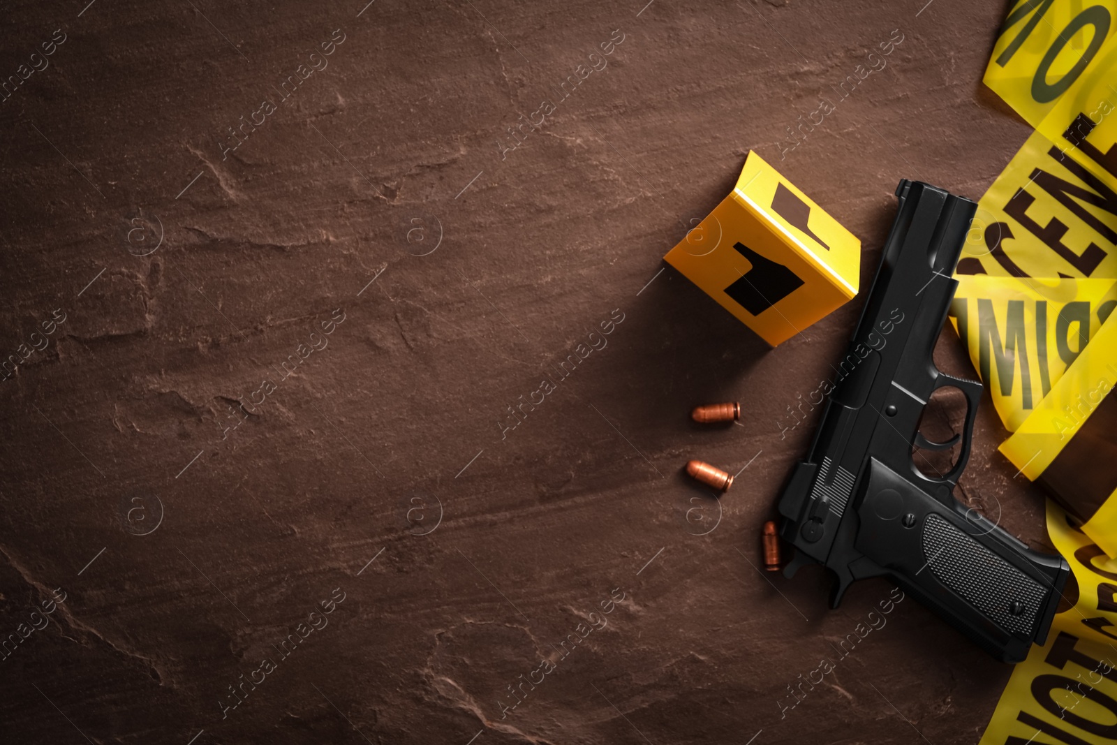 Photo of Flat lay composition with gun and bullets on black slate background, space for text. Crime scene