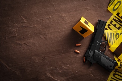 Photo of Flat lay composition with gun and bullets on black slate background, space for text. Crime scene