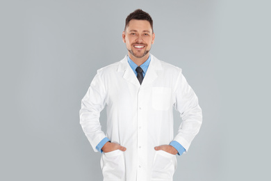 Photo of Happy man in lab coat on light grey background