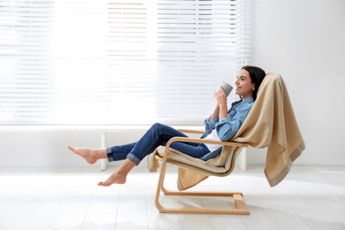 Photo of Young woman relaxing in armchair near window at home