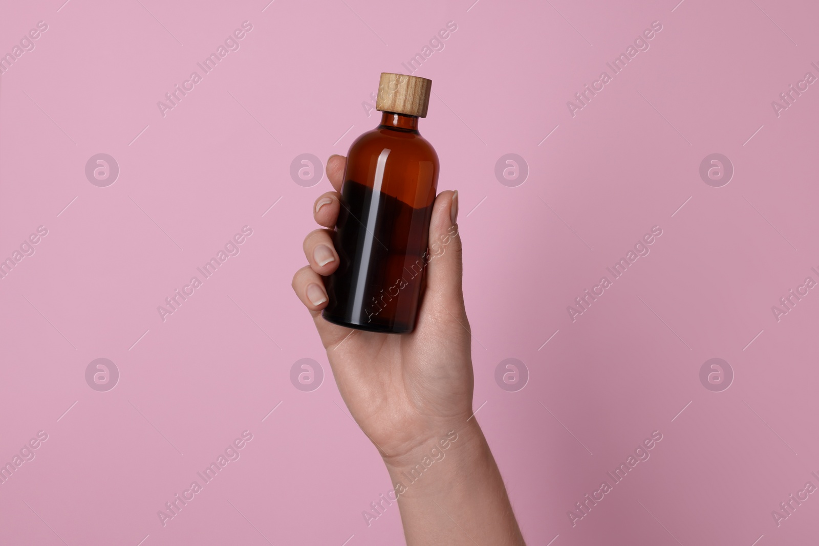 Photo of Woman holding bottle of cosmetic product on pink background, closeup