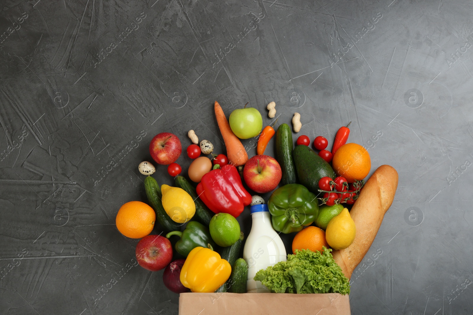 Photo of Flat lay composition with overturned paper bag and groceries on grey table