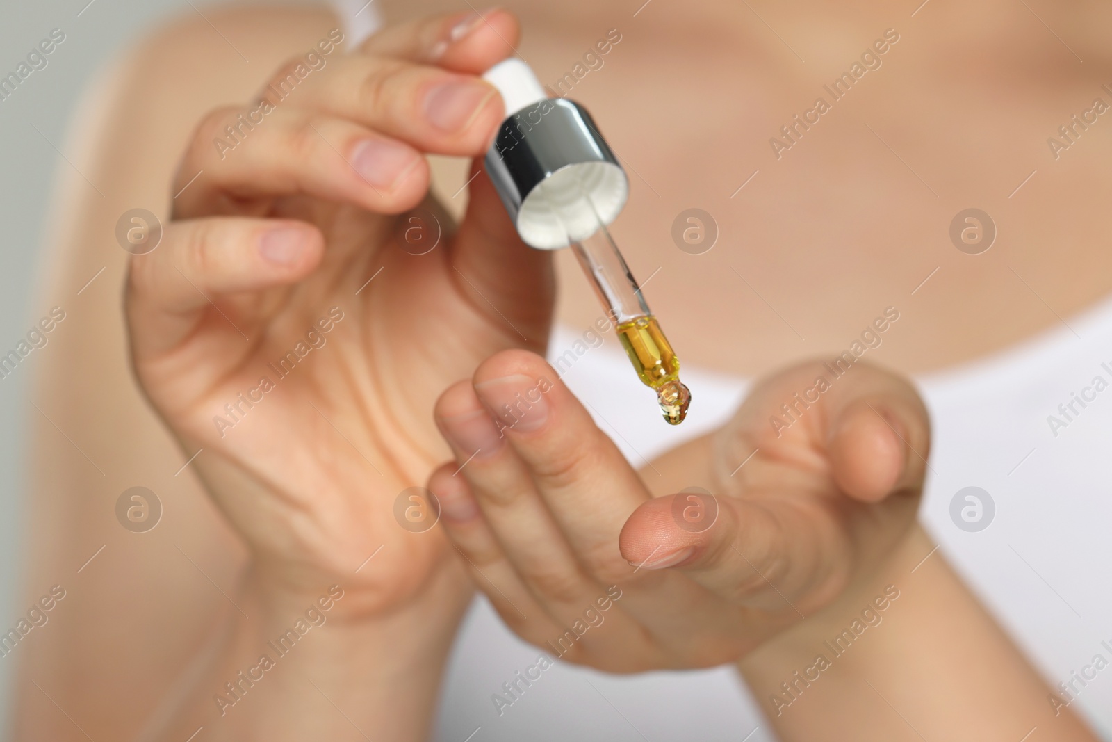 Photo of Woman applying essential oil onto finger, closeup