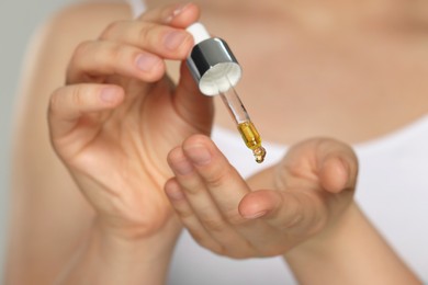 Photo of Woman applying essential oil onto finger, closeup