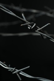 Photo of Shiny metal barbed wire on black background, closeup