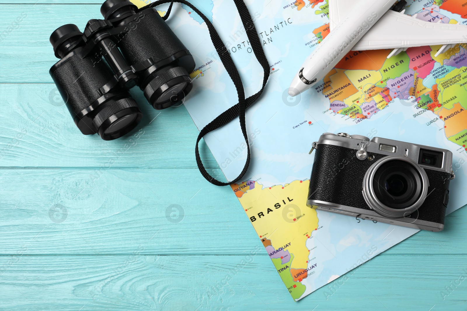 Photo of Flat lay composition with world map and different travel accessories on turquoise wooden table. Planning summer vacation trip