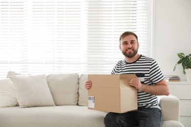 Happy young man with parcel at home