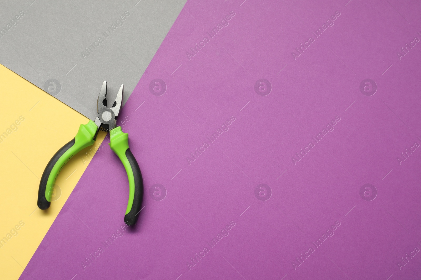 Photo of Combination pliers on color background, top view. Space for text