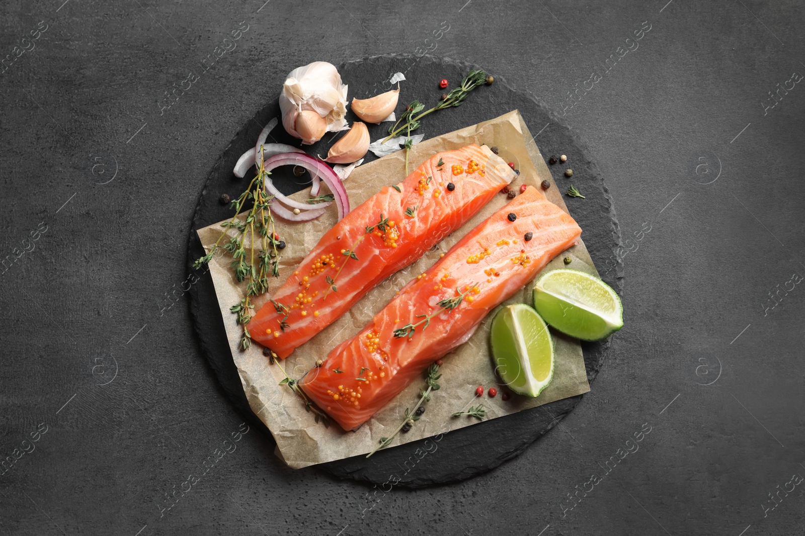 Photo of Fresh salmon and ingredients for marinade on slate plate