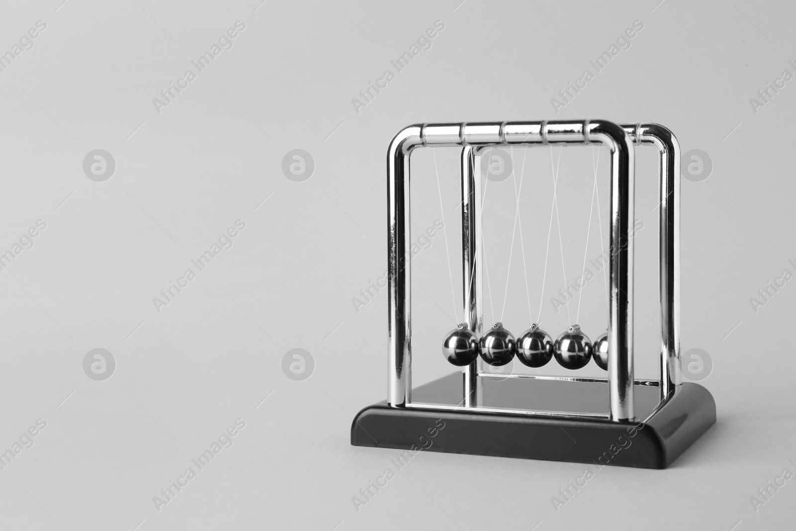 Photo of Newton's cradle on light background, space for text. Physics law of energy conservation