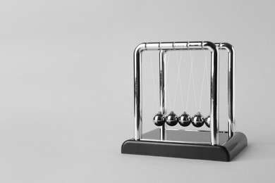 Photo of Newton's cradle on light background, space for text. Physics law of energy conservation