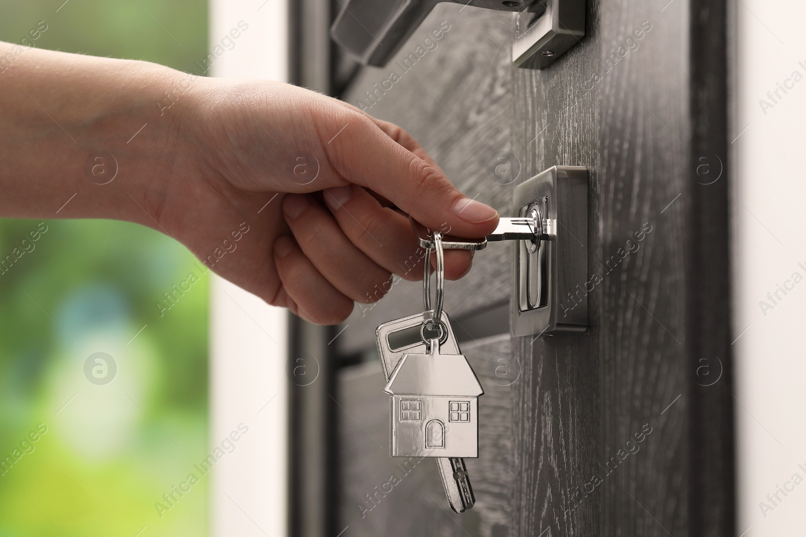 Photo of Woman unlocking door with key outdoors, closeup