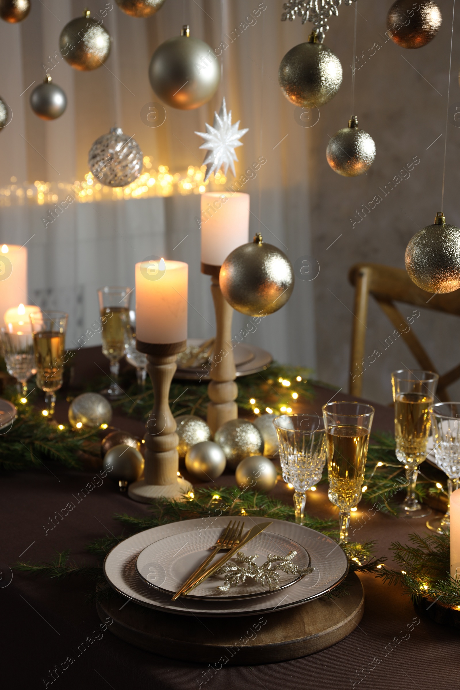 Photo of Christmas table setting with burning candles and festive decor