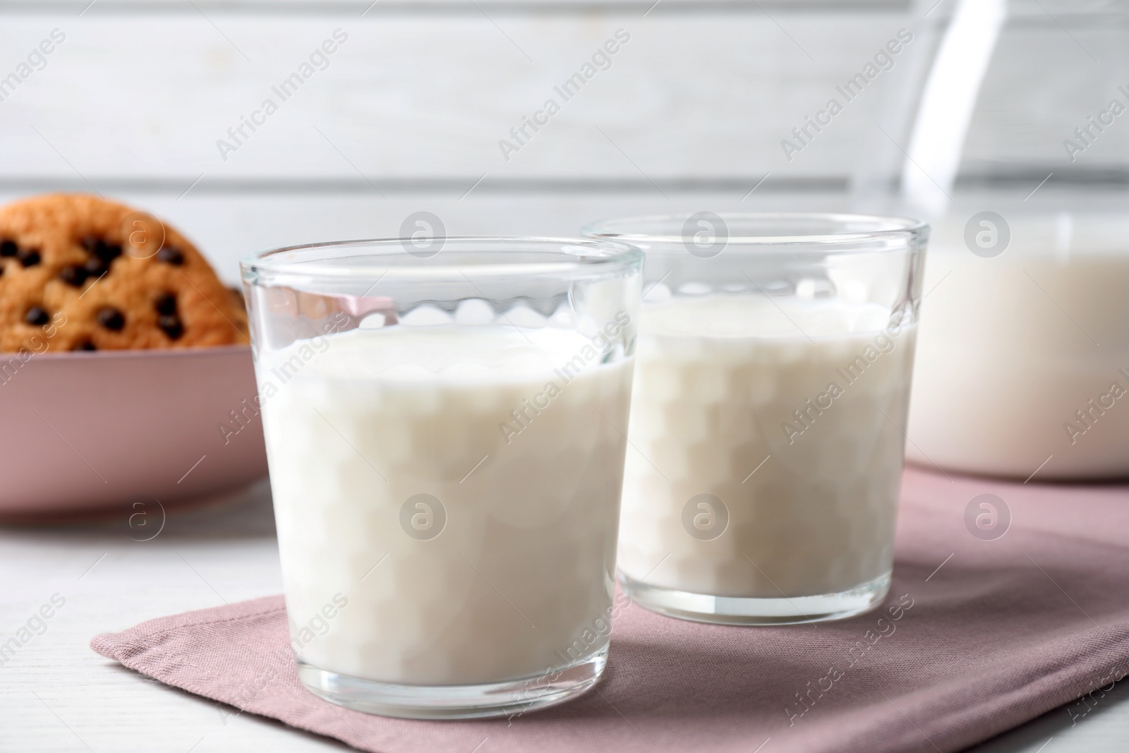 Photo of Glasses of delicious milk on light table