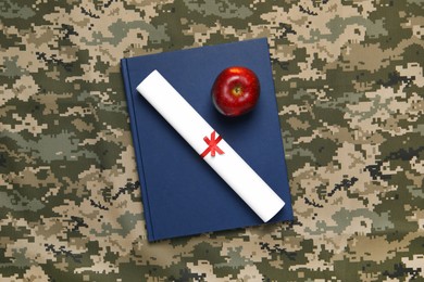 Photo of Notebook, apple and diploma on camouflage background, top view. Military education