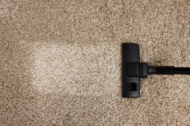 Photo of Hoovering carpet with vacuum cleaner, top view. Space for text