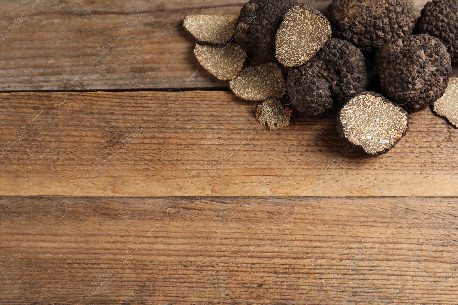 Photo of Black truffles on wooden table, flat lay. Space for text