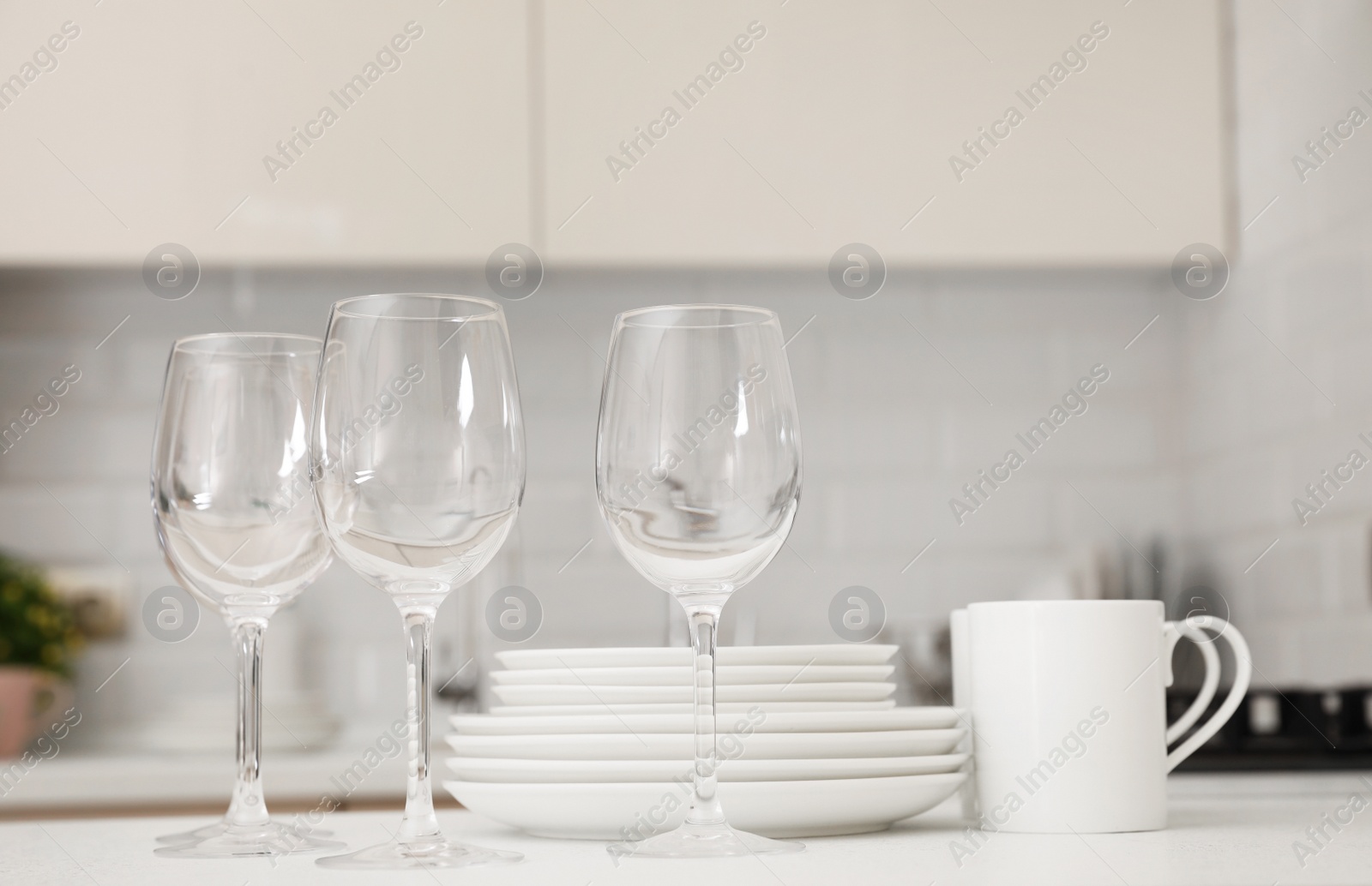 Photo of Stack of clean dishes, glasses and cups on table in kitchen