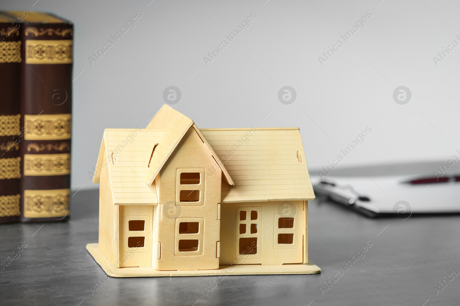 Photo of Construction and land law concepts. Books, clipboard with house model on wooden table