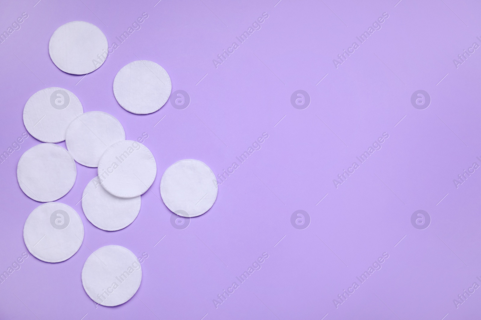 Photo of Many cotton pads on lilac background, flat lay. Space for text
