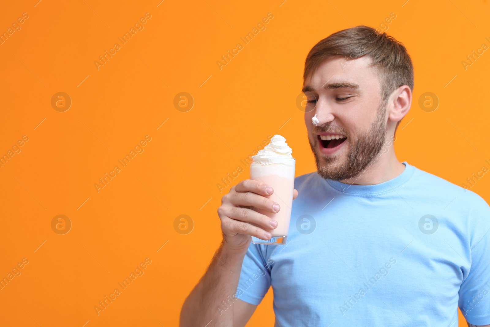 Photo of Young man with glass of delicious milk shake on color background