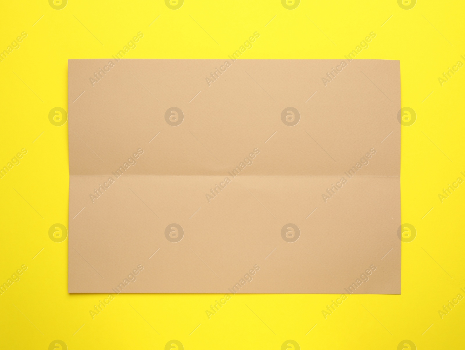 Photo of Sheet of brown paper on yellow background, top view