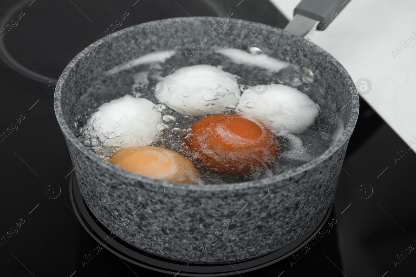 Photo of Boiling chicken eggs in saucepan on electric stove