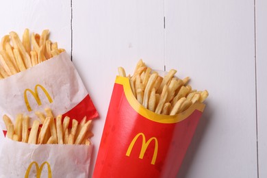 MYKOLAIV, UKRAINE - AUGUST 12, 2021: Small and big portions of McDonald's French fries on white wooden table, flat lay
