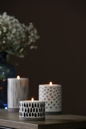 Different burning candles and flowers on wooden table