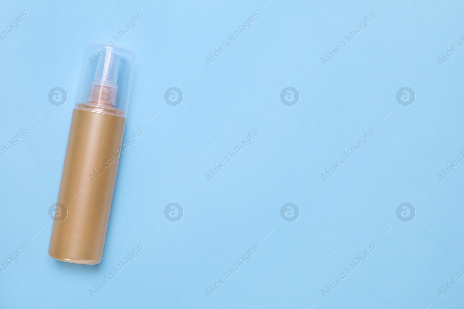 Photo of Bottle of face cleansing product on light blue background, top view. Space for text