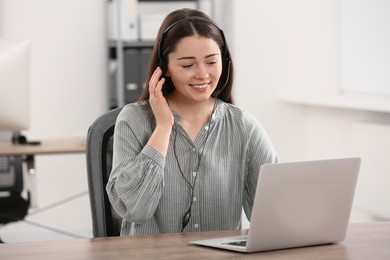 Photo of Hotline operator with headset working on laptop in office