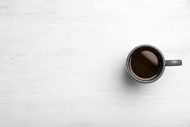 Ceramic cup with hot aromatic coffee on wooden background, top view