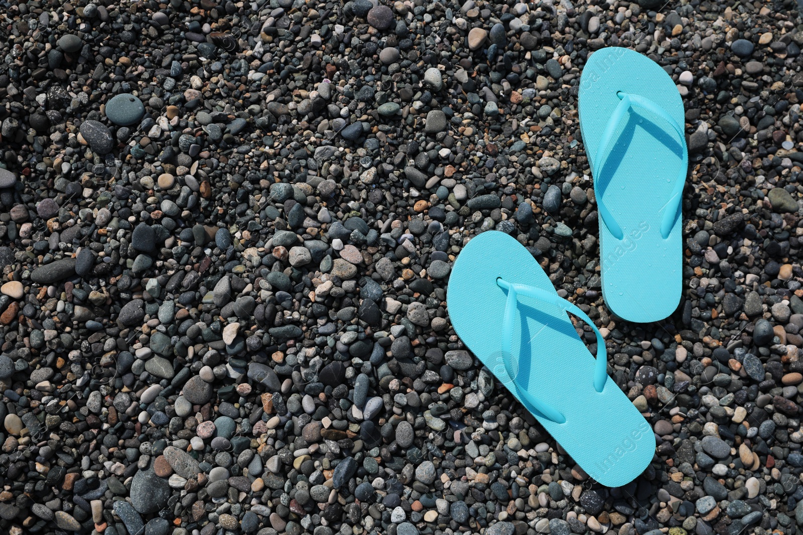 Photo of Stylish turquoise flip lops on pebble beach, flat lay. Space for text