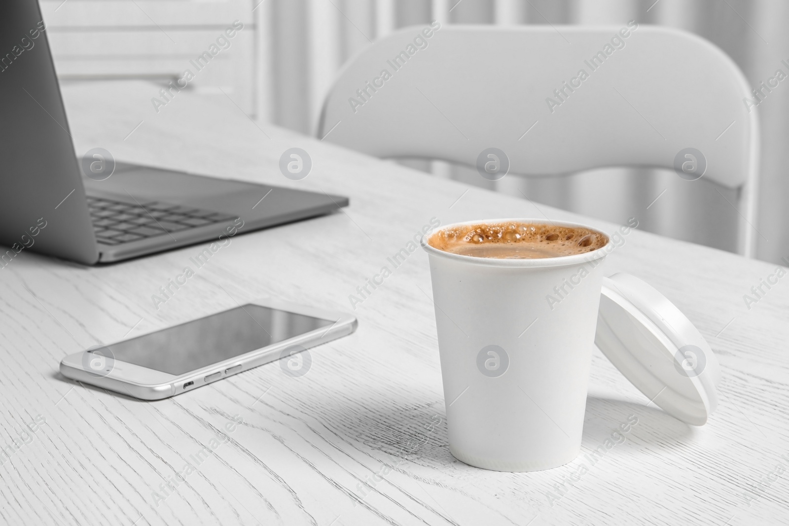 Photo of Workplace with cardboard cup of aromatic coffee on wooden table. Space for text