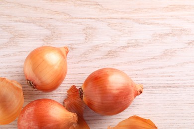 Raw ripe onions on wooden table, flat lay. Space for text