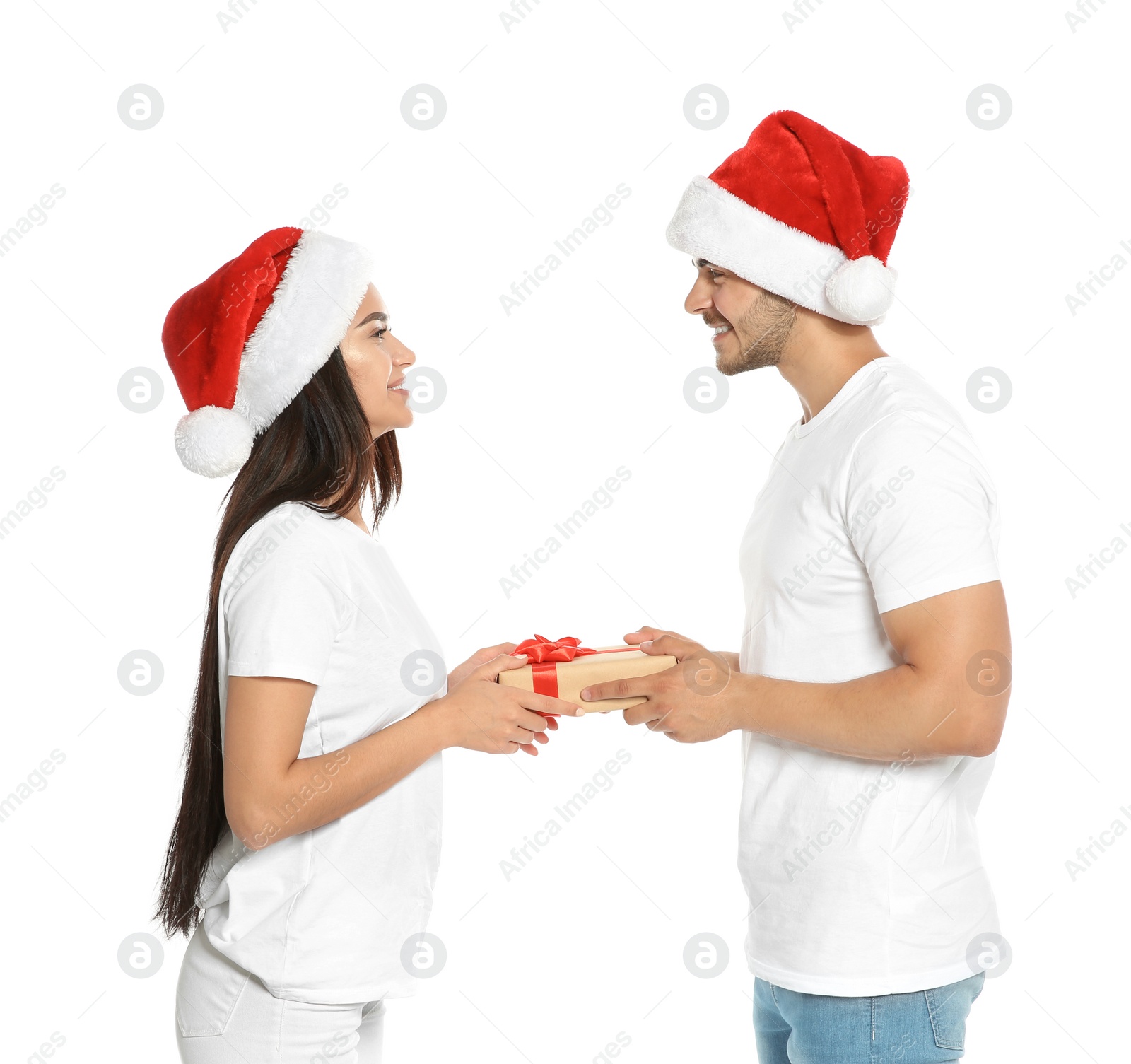 Photo of Young man giving gift box to girlfriend on white background. Happy couple celebrating Christmas