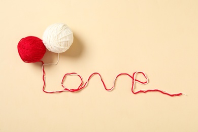 Photo of Word LOVE made of woolen yarns on beige background, flat lay