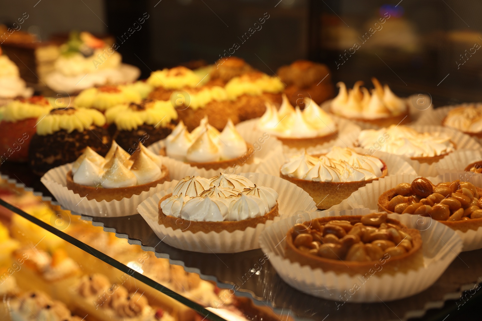 Photo of Different tasty tartlets on counter in bakery shop, closeup. Space for text