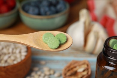 Photo of Wooden spoon of pills over foodstuff, closeup. Prebiotic supplements