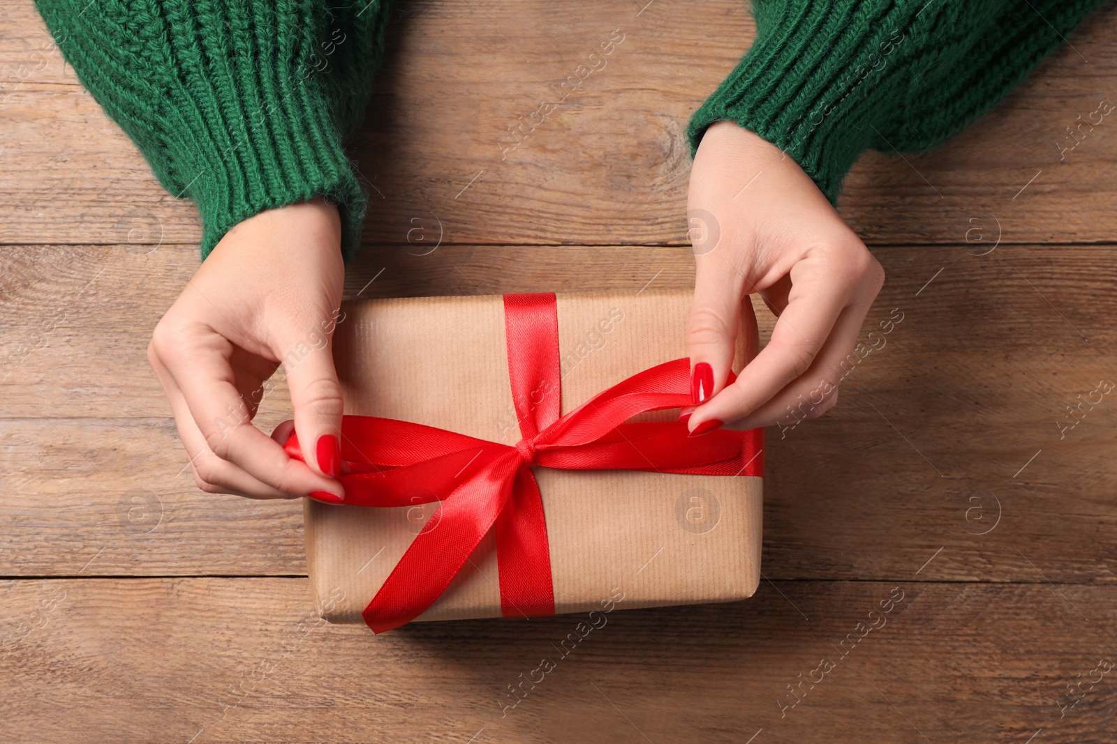 Photo of Christmas present. Woman with gift box at wooden table, top view