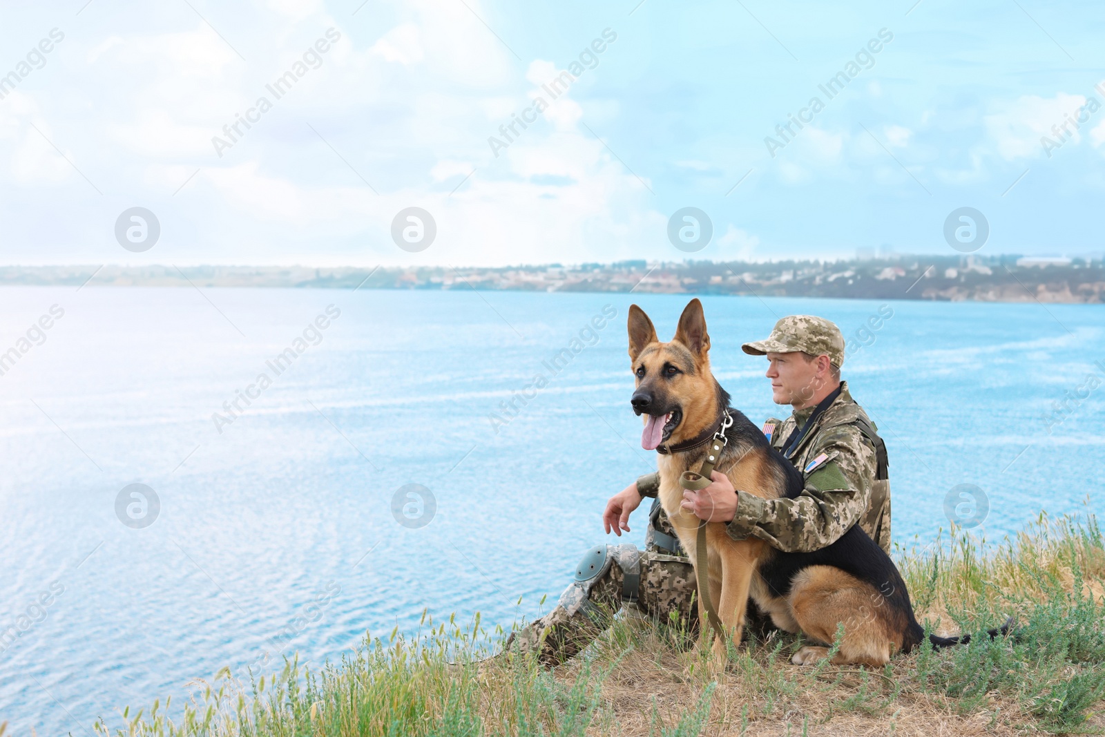 Photo of Man in military uniform with German shepherd dog near river