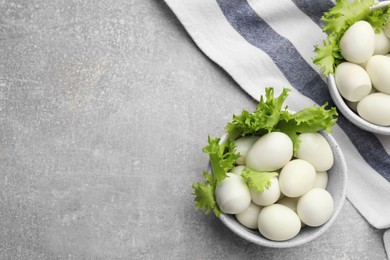 Peeled boiled quail eggs on grey table, flat lay. Space for text